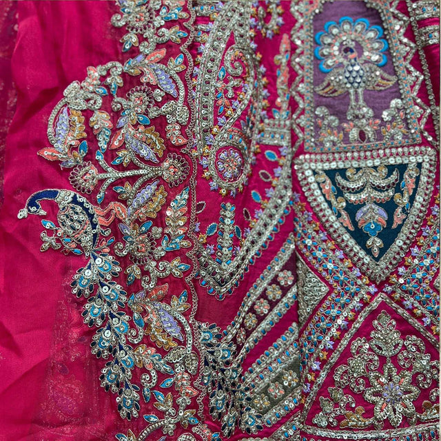 Rani pink bridal lehenga with ornate silver, teal, and gold embroidery close detail