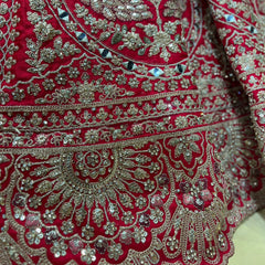 Red lehenga fabric with ornate silver and green embroidered motifs and trim