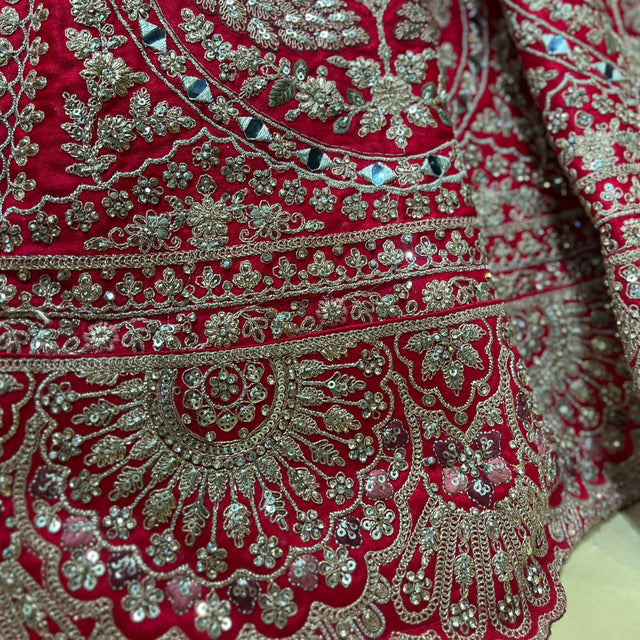 Close-up of red lehenga border with ornate silver zari embroidery and mirror accents