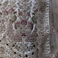 Embellished ivory fabric panel with mirror details and red-green zari embroidery close-up