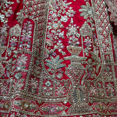 Red lehenga fabric close-up with ornate silver embroidery and stone motifs