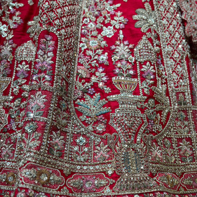 Red lehenga fabric close-up with ornate silver embroidery and stone motifs