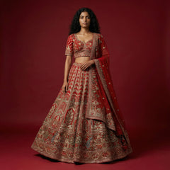 Red bridal lehenga with ornate gold motif embroidery, matching blouse and sheer dupatta.