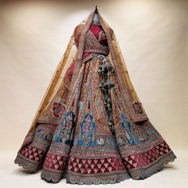 Embroidered bridal lehenga with layered flared skirt, maroon base, teal and gold motifs