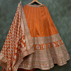 Orange raw silk bridal lehenga skirt with silver-toned embroidered hem and dupatta border
