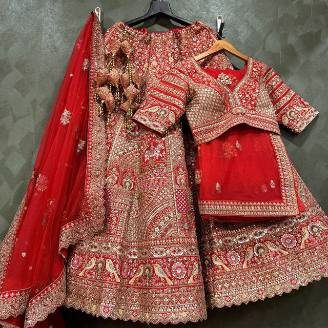 Red embroidered bridal lehenga outfit with matching blouse and net dupatta on hangers
