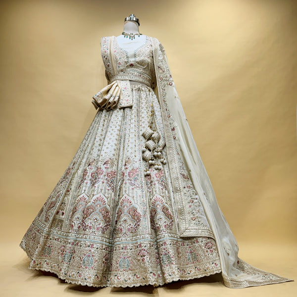 Ivory bridal lehenga with double dupatta, ornate multicolor embroidery and belt.