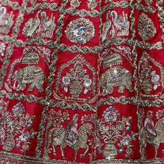 Red silk lehenga fabric close-up with silver embroidery motifs and jeweled detailing