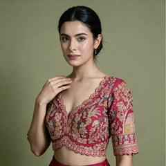 Close-up of a pink raw silk blouse with scalloped V neckline and peacock, floral and tree embroidery