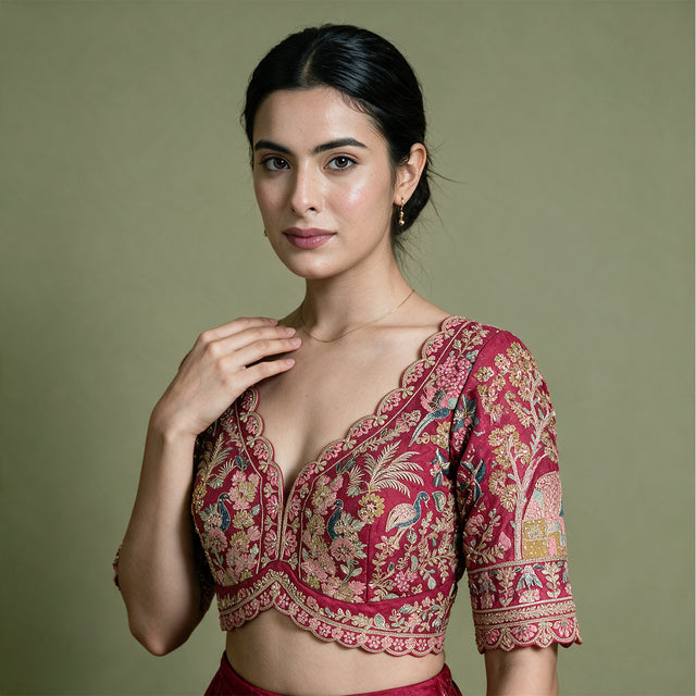 Close-up of a pink raw silk blouse with scalloped V neckline and peacock, floral and tree embroidery