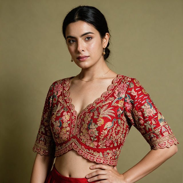 Close-up of a red raw silk blouse with scalloped V neckline and peacock, floral and tree embroidery