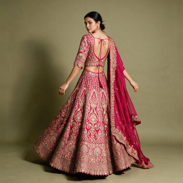 Pink bridal lehenga from back view with open back blouse, flared embroidered skirt, dupatta