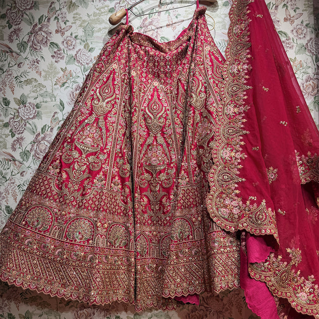 Pink and gold lehenga skirt laid out showing gold motifs, zari and stone work bands and scalloped cutwork dupatta