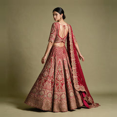 Back view of a red and gold lehenga with tie-up blouse back, full flared skirt and organza dupatta