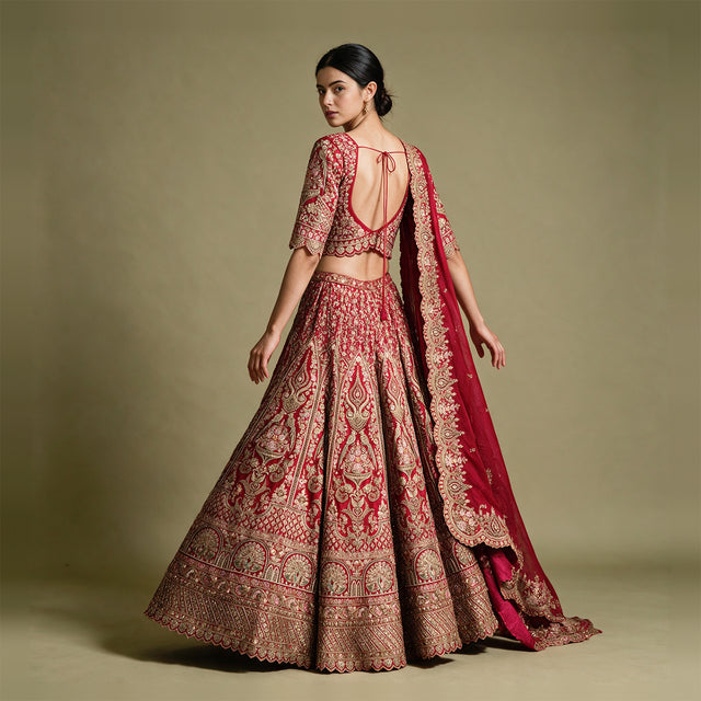 Back view of a red and gold lehenga with tie-up blouse back, full flared skirt and organza dupatta