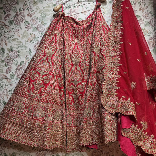 Red and gold lehenga skirt laid out showing gold motifs, zari and stone work bands and scalloped cutwork dupatta