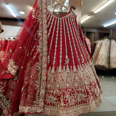 Maroon raw silk lehenga skirt hanging with gold columns, elephant procession hem and net dupatta