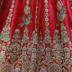Red raw silk lehenga close-up with embroidered birds, sequin medallion columns and arched floral motifs