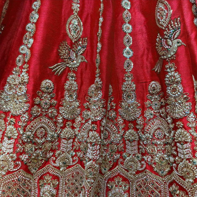 Red raw silk lehenga close-up with embroidered birds, sequin medallion columns and arched floral motifs