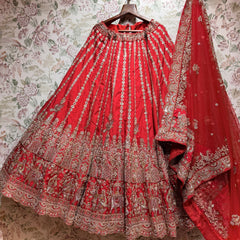 Red raw silk lehenga with elephant procession hem and embroidered net dupatta on hanger