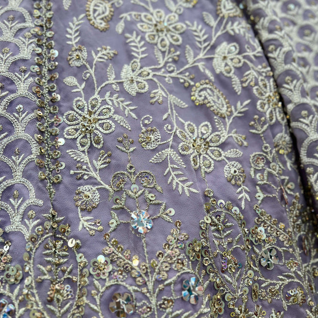 Lavender fabric swatch with ornate gold-toned thread and beadwork embroidery