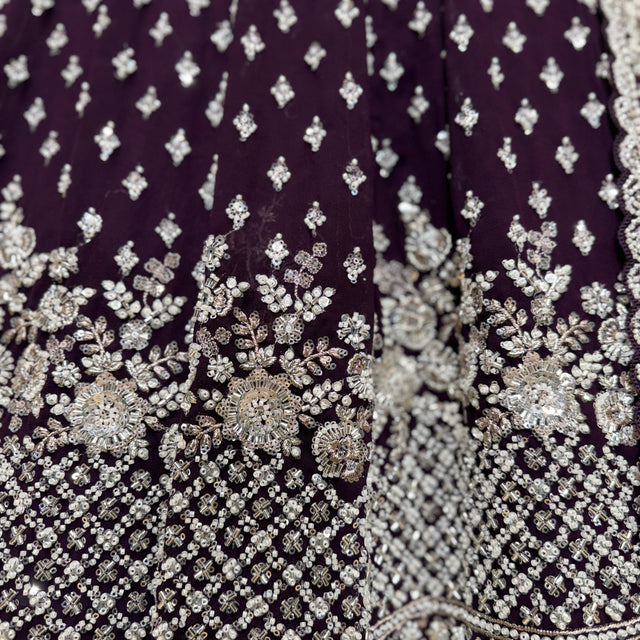 Close-up of wine lehenga fabric with dense silver beadwork and floral motifs