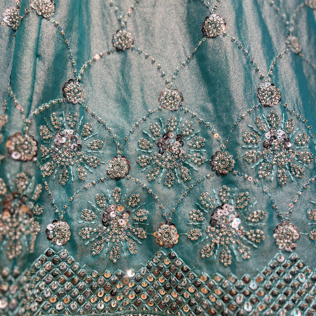Turquoise fabric with bead-and-pearl floral motifs and jeweled border at skirt hem