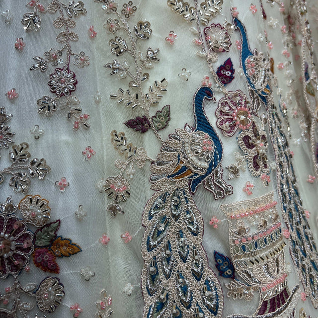 Offwhite lehenga fabric close-up with blue peacock embroidery, mirrors, beads and cutdana