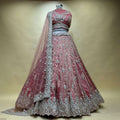 Embroidered lehenga set on mannequin, dusty pink skirt with teal-gold border