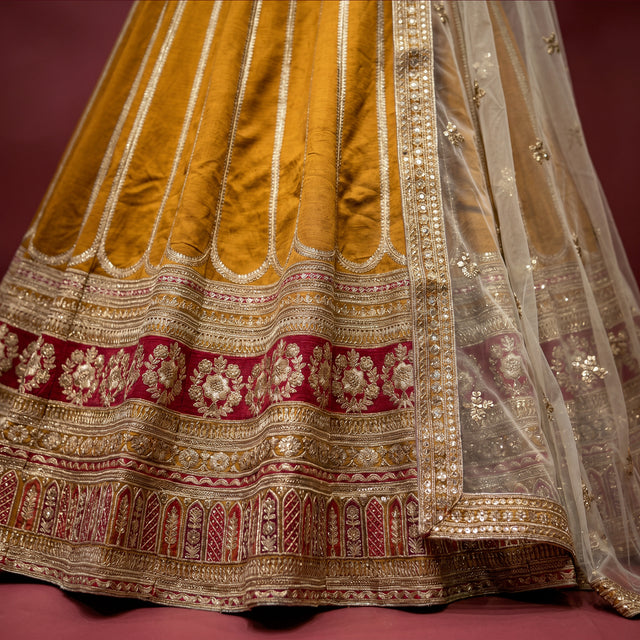 Embroidered champagne-gold lehenga skirt with ornate red border and gold hem