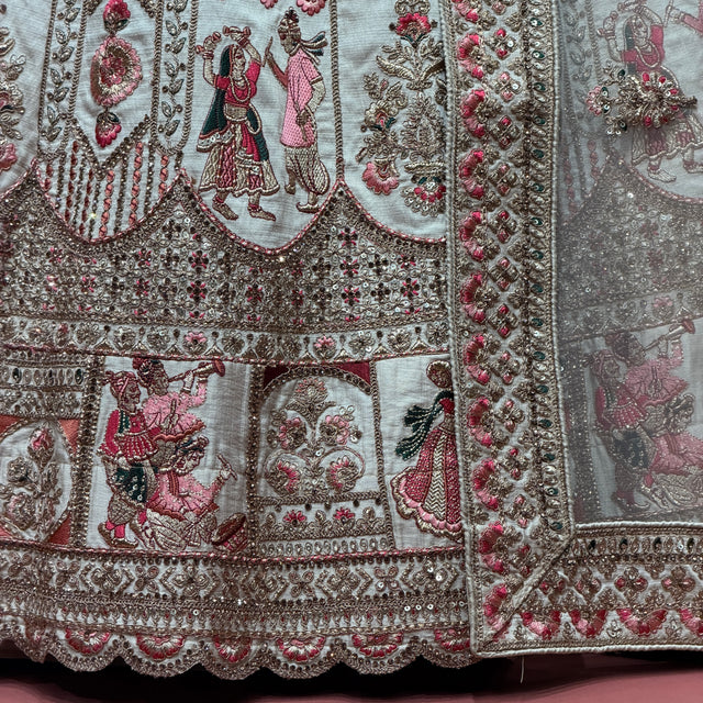 Close-up of embroidered ivory bridal lehenga hem with multicolored motifs