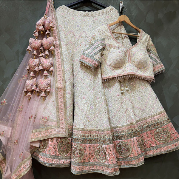Ivory Lucknowi lehenga with pink patchwork border, blouse and net dupatta on hanger