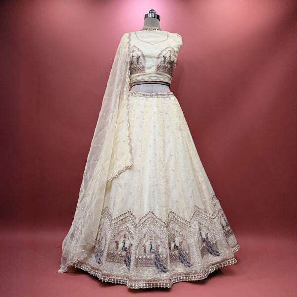 Ivory tissue silk lehenga skirt with sheer overlay and ornate peacock motif hem embroidery
