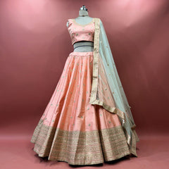 Peach raw silk lehenga set with blouse and net dupatta on mannequin