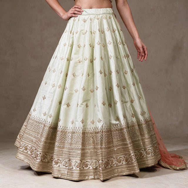 Pista green raw silk lehenga skirt with scattered gold butis and layered gold embroidered hem