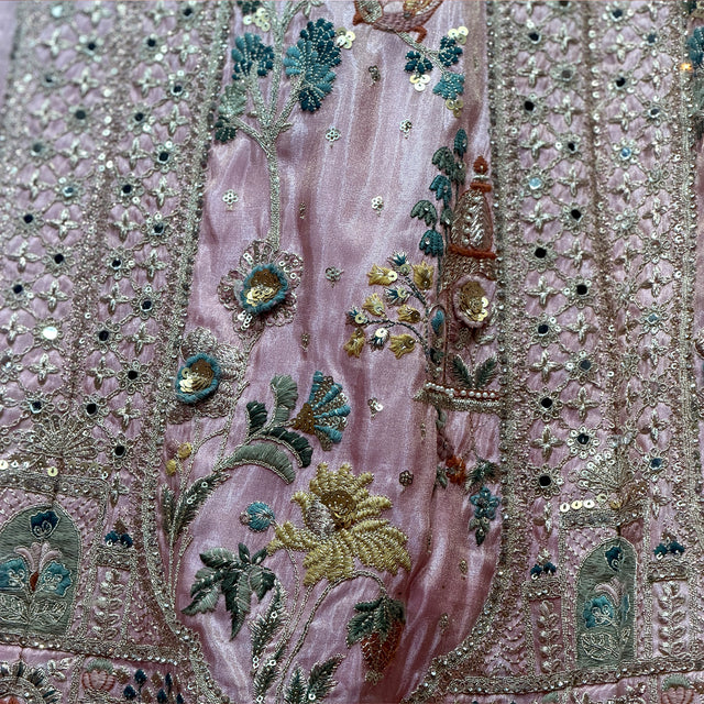 Close-up of blush lehenga fabric with dense teal-and-gold floral and bird embroidery
