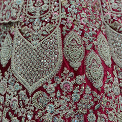 Close-up of red velvet fabric with silver, teal and pink embroidered motifs
