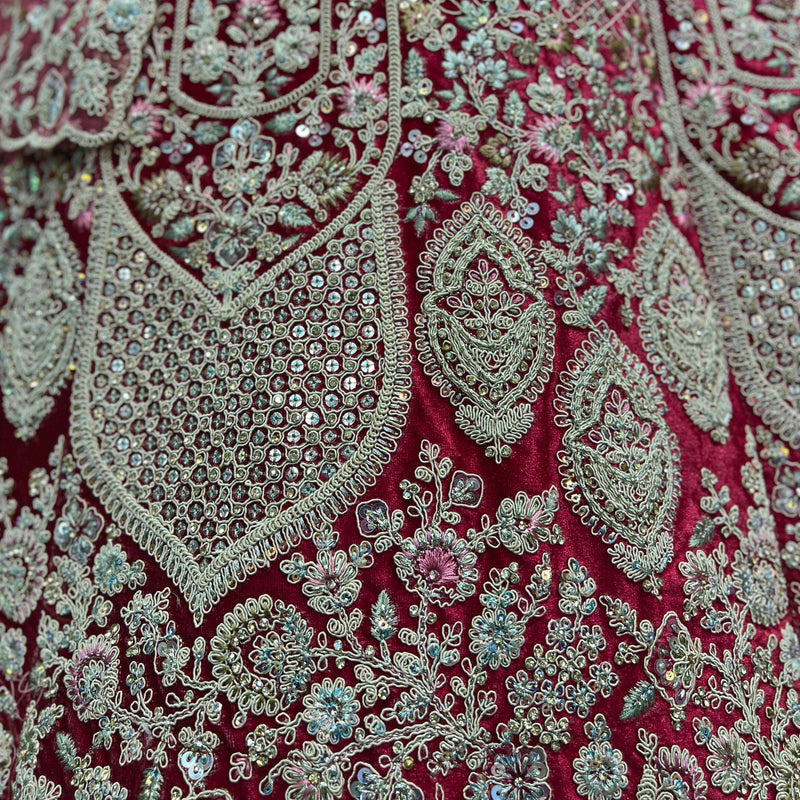 Close-up of red velvet fabric with silver, teal and pink embroidered motifs