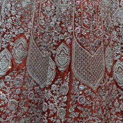 Close-up of paisley embroidery on lehenga fabric in teal, red, and silver-toned threadwork