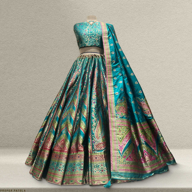 Back view of teal green lehenga with sleeveless blouse and multicolor pattern border