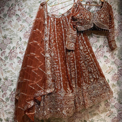 Rust net lehenga set with gold cutdana and sequin work, blouse and dupatta