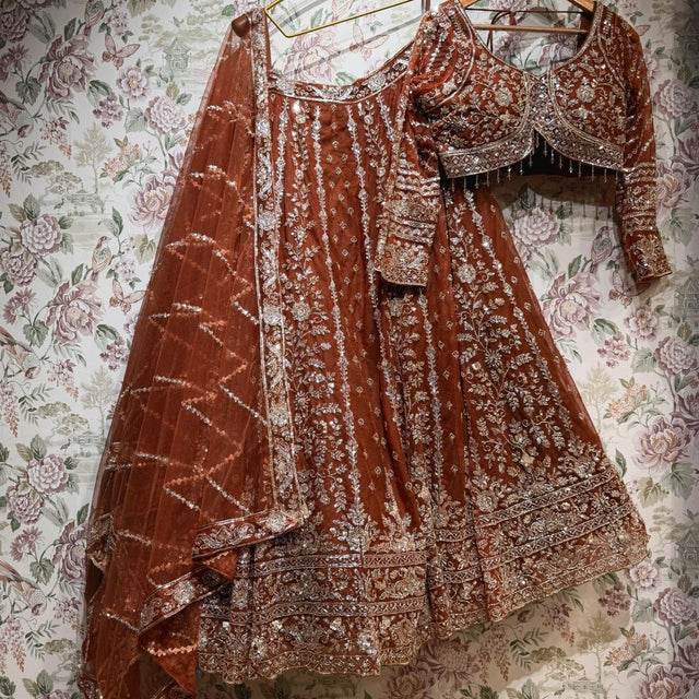 Rust net lehenga set with gold cutdana and sequin work, blouse and dupatta