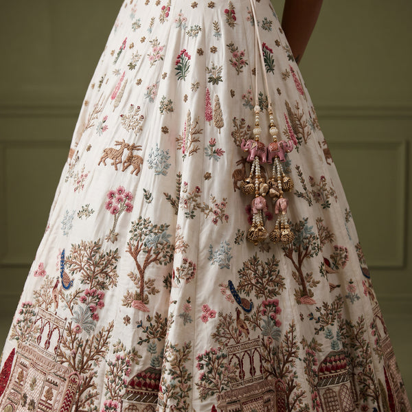 White lehenga skirt with multicolor floral and tree prints, ornate border trim