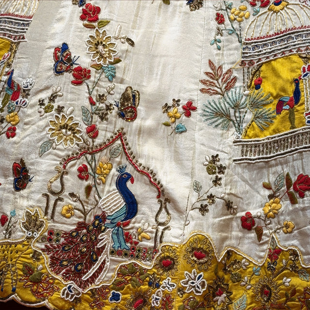 Ivory lehenga fabric close-up with multicolour bird, floral, moti & cutdana work
