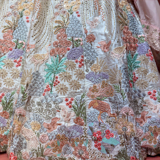 Close-up of off-white fabric with colorful resham and zari animal and floral motifs