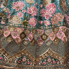 Embroidered teal lehenga bodice and hem with pink floral motifs and gold accents