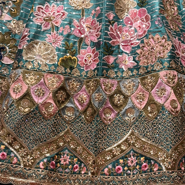 Embroidered teal lehenga bodice and hem with pink floral motifs and gold accents