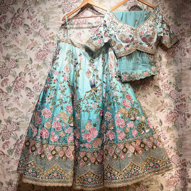 Sky blue floral lehenga dress on hanger with gold decorative border and full skirt