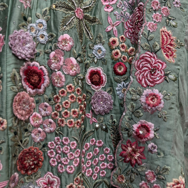 Embroidered sage green fabric with pink and purple floral threadwork motifs