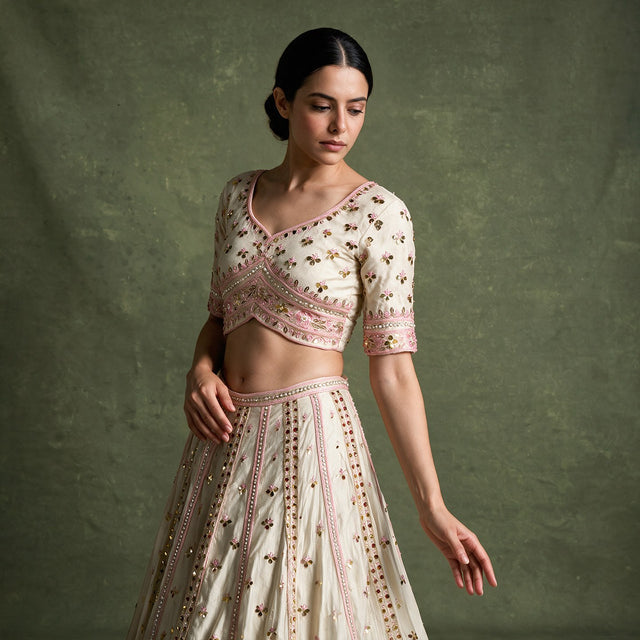 Close-up of the ivory cross-over blouse with pink embroidered band and cuffs, and the skirt with pink embroidery lines and mirror discs